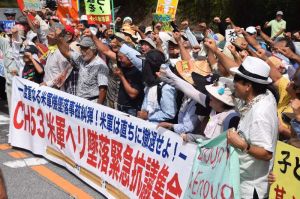 米軍ヘリの炎上事故に対する緊急抗議集会で、北部訓練場の全面返還を訴える参加者=15日午後0時58分、東村高江の北部訓練場メインゲート前