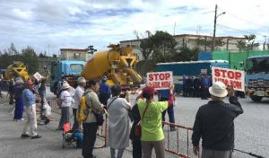 出入りする工事用車両に対し、新基地建設に抗議するプラカードを掲げる市民=27日午後0時10分すぎ、名護市辺野古のキャンプ・シュワブゲート前