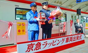 京急ラッピング車両の出発式に臨む沖縄都市モノレールの新崎康人さん(左)と指導役を務めた京浜急行電鉄の加瀬晋一さん(右)=8日、沖縄都市モノレール那覇空港駅