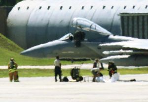 緊急着陸したF15の機体下部に白いシートを広げる作業員や消防隊員ら=25日、米軍嘉手納基地(読者提供)