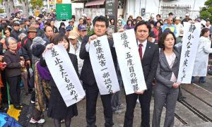 判決を受け、那覇地裁沖縄支部前で垂れ幕を掲げる住民側の弁護士ら=23日午前、沖縄市