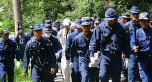 機動隊員に警護され、東村道から北部訓練場に向かうヘリパッド建設工事関係とみられる作業員(中央)=12日、東村高江(仁尾淳史さん提供)