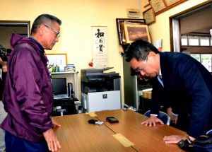 部品落下を受けて玉城自治会長(左)に謝罪する沖縄防衛局の中嶋局長=9日、伊計自治会