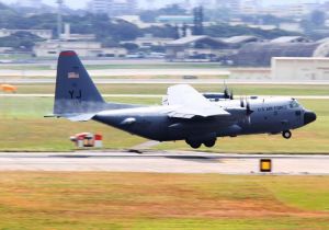 右翼から白い霧状の燃料を放出しながら着陸するC130輸送機=21日正午ごろ、米軍嘉手納基地(読者提供)