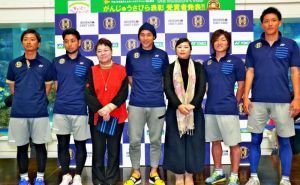 記者会見でポロシャツをPRする「沖縄SV」の高原代表(中央)。右から3人目は神村琉球びんがた事業協同組合副理事長、同5人目は安座間那覇伝統織物事業協同組合理事長=11日、北中城村・イオンモール沖縄ライカム