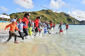 水上運動会がスタートし、一斉に海へ駆け出す参加者=15日午前、渡名喜村・あがり浜(落合綾子撮影)
