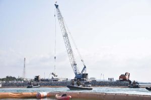 海に投下された石材の上に被覆ブロックを設置する作業が続いた=26日午前8時59分、名護市辺野古