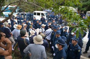 ヘリパッド建設に抗議する市民を県道70号線の道路脇に排除する機動隊員=17日午前、北部訓練場N1地区表側出入口付近