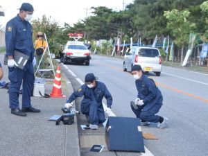 事故現場で鑑識作業する県警職員=24日午前8時40分ごろ、米軍キャンプ・シュワブゲート前
