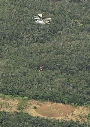 米軍北部訓練場内で小型重機を運ぶヘリ=9日午後2時45分、国頭村安波(琉球朝日放送提供)