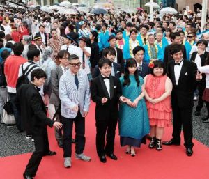 沿道を埋め尽くすファンの声援に答えレッドカーペットを歩く出演者=22日、那覇市・国際通り