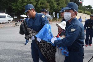 女性機動隊員の対応を求め、スカートを履いて座り込む女性を排除する機動隊=25日午前9時9分、名護市辺野古、米軍キャンプ・シュワブ工事車両用ゲート前