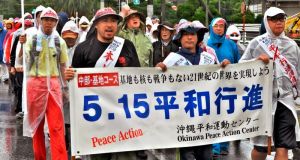 雨の中、基地反対の声を上げて行進する参加者=13日正午、北中城村瑞慶覧