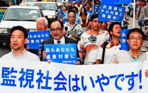 「共謀罪」反対を訴え横断幕やプラカードを手にデモ行進する弁護士ら=12日午後、那覇市牧志