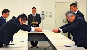 中嶋浩一郎沖縄防衛局長(手前左)に要望書を手渡す県PTA連合会の石川謙会長=日、嘉手納町・同局