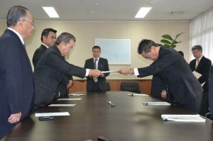 沖縄防衛局の中嶋浩一郎局長(右)にヘリ窓落下の抗議文を手渡す金城勉公明県本代表=14日、嘉手納町・沖縄防衛局