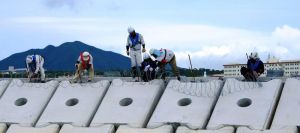 「K4」護岸上に有刺鉄線を設置する作業員=4日、名護市辺野古・キャンプ・シュワブ沿岸(ヘリ基地反対協抗議船提供)