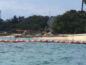 重機を使い、砂浜に鉄板を敷く作業員=4日午前、名護市辺野古