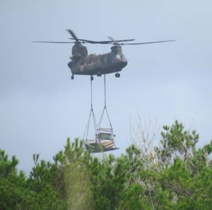 トラックをつり下げて、搬入する陸上自衛隊の大型輸送ヘリCH47=13日午前10時すぎ、東村高江と国頭村安波の境付近
