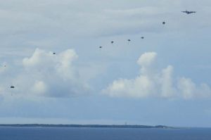 米軍機から次々と降下するパラシュート=30日午前9時30分すぎ、うるま市勝連・津堅島訓練水域の上空