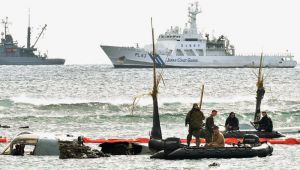 米兵が機体の撤去作業をする中、海上保安庁の巡視船は沖合で停泊したままだった=15日午前11時5分、名護市安部の海岸