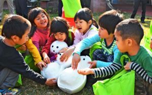 「冷たーい」と雪だるまをさわり喜ぶ園児たち=19日、名護市役所