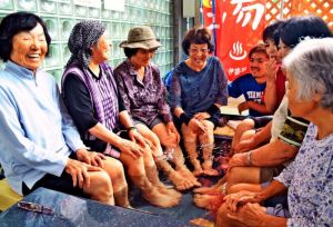 「ギンバル温泉」の足湯を楽しむ人たち。心地よさに会話も弾む=2日、金武町伊芸地区公民館