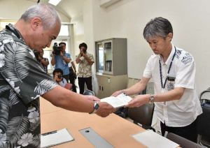 事業行為通知書を県に提出する沖縄防衛局職員(右)=12日午後4時59分、名護市・県北部保健所(金城健太撮影)