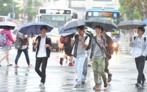 大雨の中、傘をさして歩く人たち=13日午前、那覇市久茂地