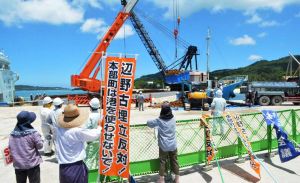 新基地建設に反対する市民が見守る中、運搬船に積み込まれる土砂=25日、本部港塩川地区