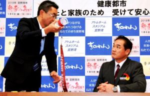 保育園で発見された同型の部品を持って佐喜真淳宜野湾市長(右)に説明する中嶋浩一郎沖縄防衛局長=11日、宜野湾市役所