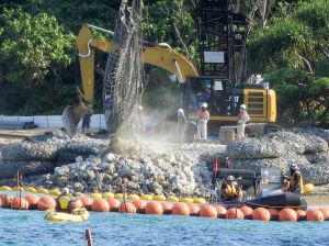 辺野古新基地建設に向けた護岸工事で、粉じんを上げながら海中に投下される石材=8日午後4時半ごろ、名護市辺野古・米軍キャンプ・シュワブ