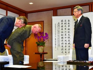 翁長雄志知事(右)に頭を下げて謝罪するニコルソン四軍調整官(左から2人目)ら=20日午後3時半、沖縄県庁