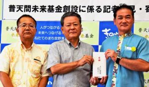 佐喜真淳宜野湾市長(右)に目録を手渡す國場組の玉城徹也社長(中央)、渡慶次道昌執行役員常務=3日、宜野湾市役所