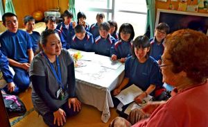 新垣ハルさん(右)から、宮森小のジェット機墜落当時の話を聞く伊波中の生徒ら=5月2日、読谷村内