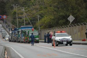 パトカーに先導され米軍キャンプ・シュワブゲートに向かう工事車両=3日、名護市辺野古