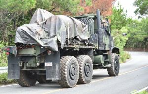 ヘリの残骸を載せ、県道70号を北上する米軍の大型トラック=20日午前10時21分、東村高江