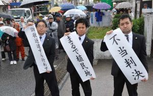 訴えが却下され、「不当判決」など書かれた幕を掲げる弁護団=9日午後2時3分、沖縄市知花・那覇地方裁判所沖縄支部前