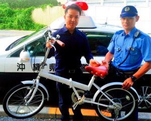 発見した沖縄署員から、自転車を受け取った末広尚希さん(左)=10月2日、宜野湾市