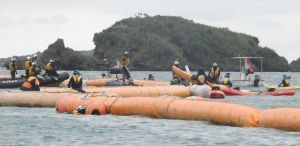 石材の投下作業が続く「K4」護岸建設現場近くでカヌーに乗って抗議の声を上げる市民と、監視する海上保安庁の職員=2日、午前9時7分、名護市辺野古、米軍キャンプ・シュワブ沿岸