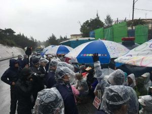 降りしきる雨の中、新基地建設に抗議し座り込みをする市民ら=14日、名護市辺野古の米軍キャンプ・シュワブゲート前