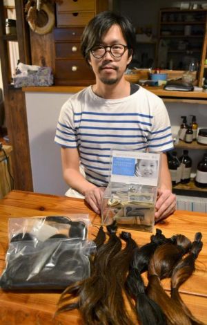 胸まであった髪を切って寄付した川名さん。客から寄付された髪やお金はまとまってからJHDACへ送るという=読谷村座喜味・hair room botanika