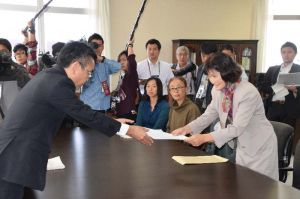 中嶋浩一郎局長(左)にオスプレイ配備撤回などを盛り込んだ決議文を手渡す仲嶺久美子区長=20日、沖縄防衛局