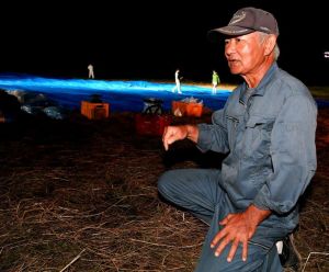 事故後初めて牧草地に足を踏み入れ、「めちゃくちゃだ」と落胆する西銘晃さん=日午後8時分、東村高江(渡辺奈々撮影)