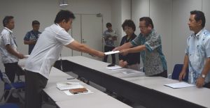 沖縄防衛局企画部の池田眞人次長(左)に、米軍のパラシュート降下訓練に対する抗議文を手渡す社大党の大城一馬委員長(右から2人目)ら=24日、沖縄防衛局
