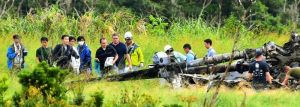 米軍の立ち会いの下、炎上した米軍ヘリの機体周辺で調査を行う県と防衛局職員ら(左側)=17日午後2時すぎ、東村高江(渡辺奈々撮影)