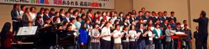 ステージで熱唱する保護者や教職員、地元住民ら=宜野湾市民会館(同中PTA提供)