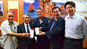 寄付金を贈呈する(左から)宮里達也さんと宮城信雄さん、琉球華僑総会の張本会長と徐顧問、那覇分処の呉領事部長=21日、那覇市・琉球華僑総会事務所