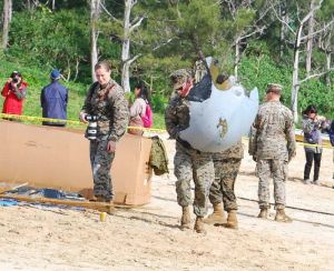 オスプレイの機体の破片を運ぶ米兵=15日午前10時40分ごろ、名護市安部(浦崎直己撮影)