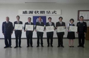 照屋雅浩署長(右)から感謝状を贈られたコザ信金開南支店の宮城武支店長(左から4人目)と職員ら=那覇市・中央消防署(提供)